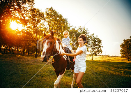 Little girl riding on a horseback with her mother Little girl riding on a horseback with her mother 38237017