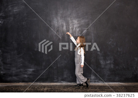 girl writing something with a chalk on blackboard girl writing something with a chalk on blackboard 38237625