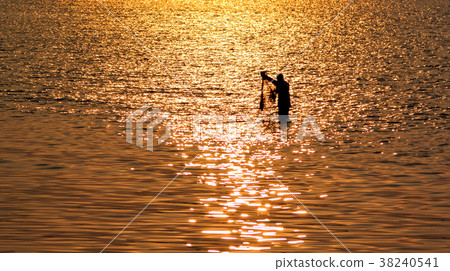 Fisherman with net in sea with sunset reflection Fisherman with net in sea with sunset reflection 38240541