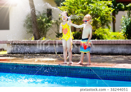 Kids play with water hose at swimming pool. 38244051