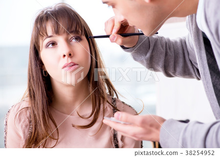 Man doing make-up for cute woman in beauty salon Man doing make-up for cute woman in beauty salon 38254952