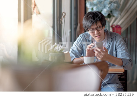 Young Asian man using smartphone in cafe 38255139
