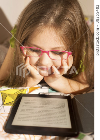 Little caucasian girl with a e-book in the bed Little caucasian girl with a e-book in the bed 38255482