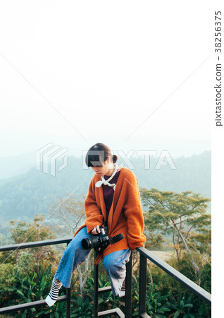 Asian woman in morning light sit on fence mountain 38256375