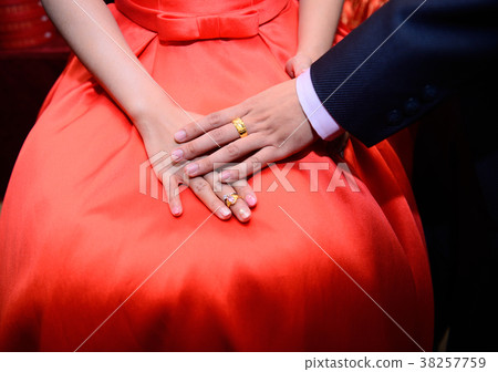The groom puts the ring in his hand on the bride's hand 38257759