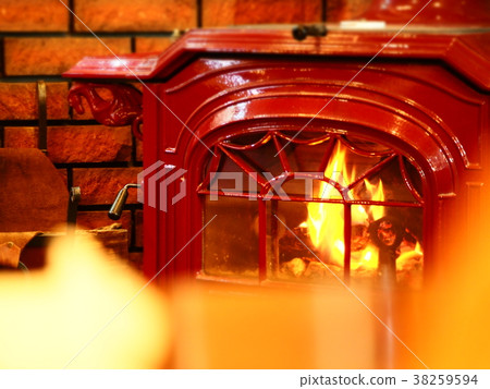 A bright red wood-burning stove that burns brightly against a brick wall 38259594