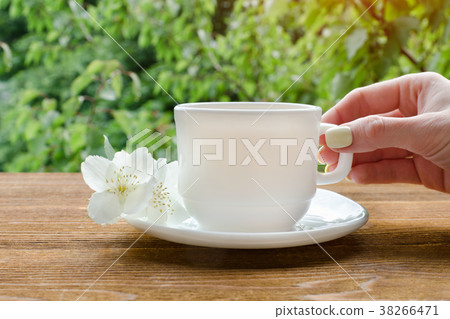 Female hand with white mug of tea and jasmine 38266471