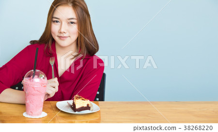 Happy attractive young asian woman siting at a table smiling at Happy attractive young asian woman siting at a table smiling at 38268220