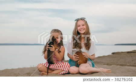 Two children playing which dogs on the sand on the Two children playing which dogs on the sand on the 38276102