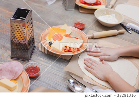 Children's hands smoothen dough for pizza on a woo 38281310
