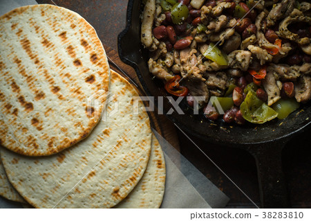 Tortilla on parchment and frying pan with filling Tortilla on parchment and frying pan with filling 38283810