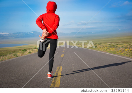 Fitness woman runner warming up on country road 38291144