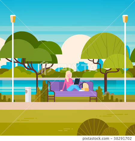 Young Woman Sitting On Bench In Park Using Laptop Young Woman Sitting On Bench In Park Using Laptop 38291702