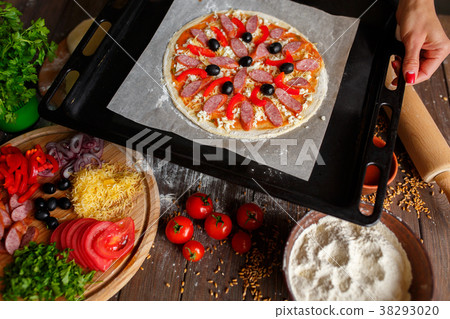 Raw pizza with ingredients on baking tray 38293020