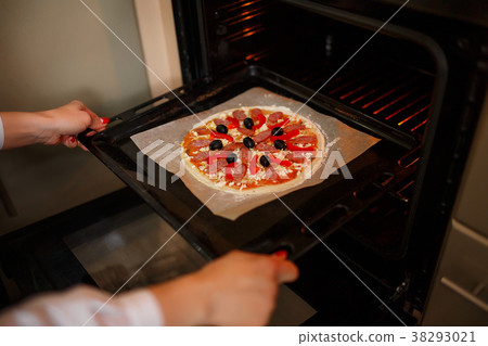 Woman put Raw pizza with ingredients and tomato 38293021
