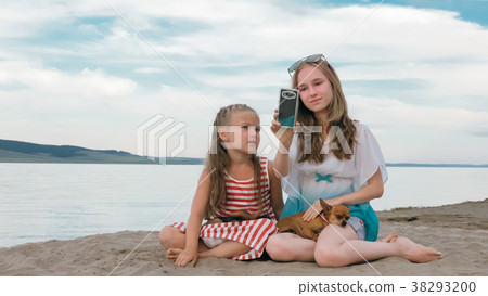 Two teenage are sitting on a sandy beach, on the 38293200