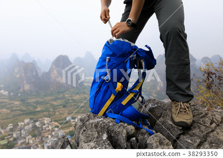 hiker packing the backpack on mountain cliff edge hiker packing the backpack on mountain cliff edge 38293350