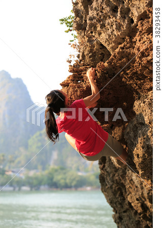 Young woman rock climber climbing on seaside cliff 38293458