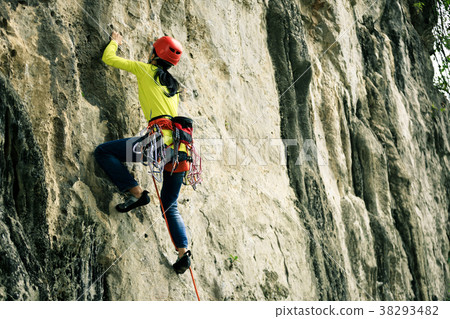 female rock climber climbing on mountain cliff 38293482