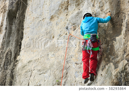 female rock climber climbing on mountain cliff 38293864