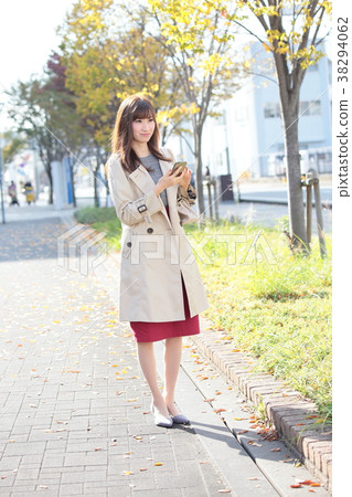 Young woman operating a smartphone on the sidewalk 38294062