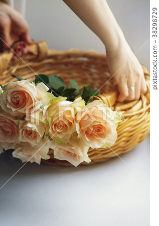 Women's hands hold a basket with bunch of roses 38298729