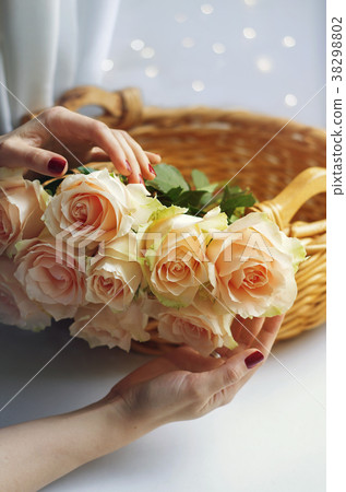 Women's hands hold a woven basket with cream rose 38298802