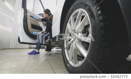 Young woman in blue gloves is cleaning interior of 38302775