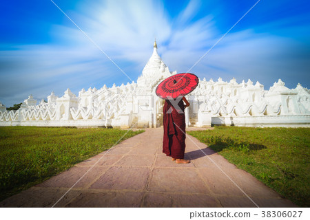 Asian young monk holding red umbrellas Asian young monk holding red umbrellas 38306027