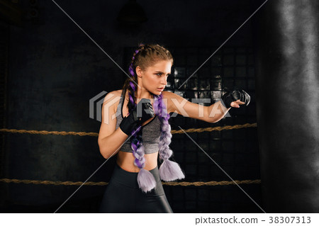 Young woman trains in boxing ring with heavy Young woman trains in boxing ring with heavy 38307313