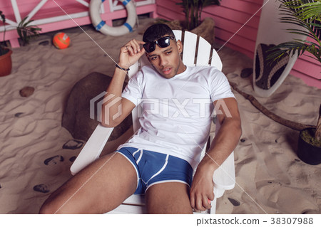 Sexy man in a white T-shirt is sitting on a wooden 38307988