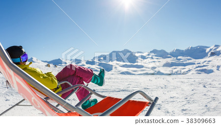 Image of sporty woman in helmet sitting at snowy 38309663