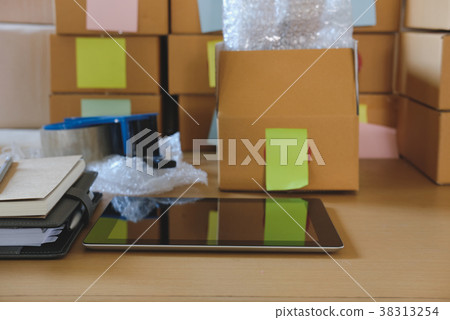 tablet, packing accessories at workplace of startup small business owner. cardboard parcel box for online selling. entrepreneur, SME seller desk. e-commerce, shipping concept 38313254
