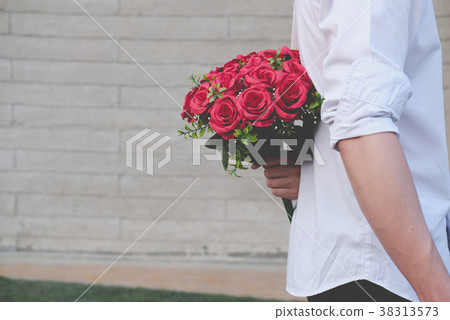 man holding bouquet of red roses behind his back. boyfriend surprise girlfriend with flower in valentine's day. celebrate anniversary, love, relationship concept 38313573