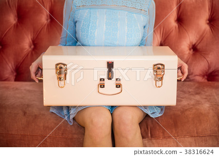 Woman sitting on sofa holding chest box 38316624