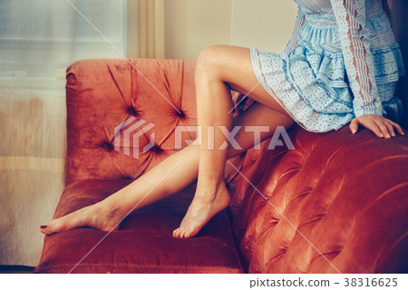 Long beautiful female legs and bare feet on sofa 38316625