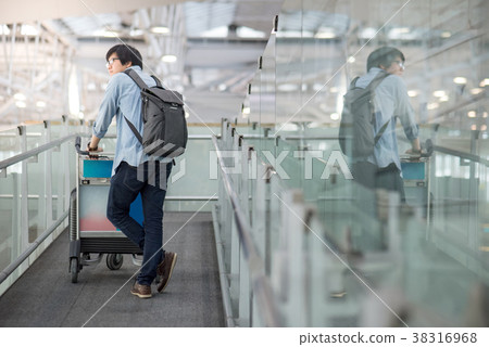 young asian man walking with trolley in airport young asian man walking with trolley in airport 38316968