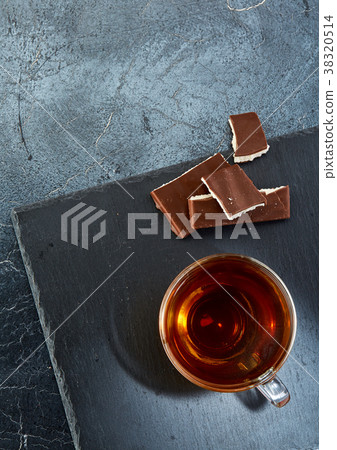 glass cup of black tea with chocolate pieces on a glass cup of black tea with chocolate pieces on a 38320514