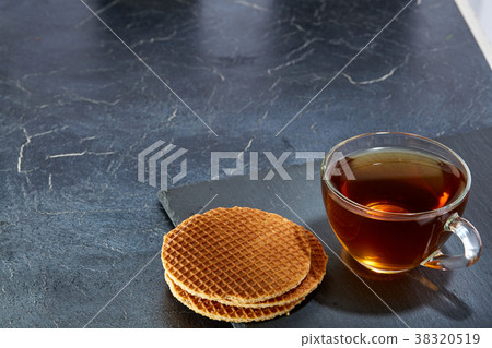 A glass cup of black tea with waffles on a dark A glass cup of black tea with waffles on a dark 38320519