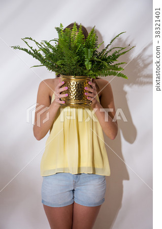 A girl is holding pot with a fern 38321401