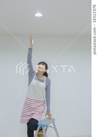 Woman replacing a light bulb Woman replacing a light bulb 38322976