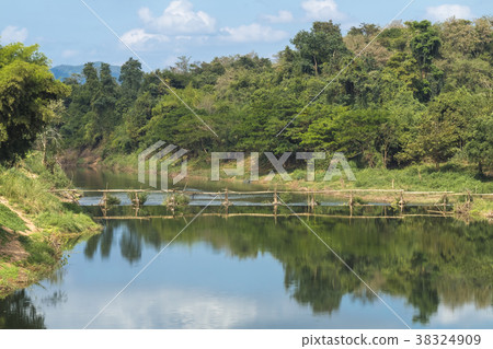 Wooden bridge in forest reflects on water  38324909