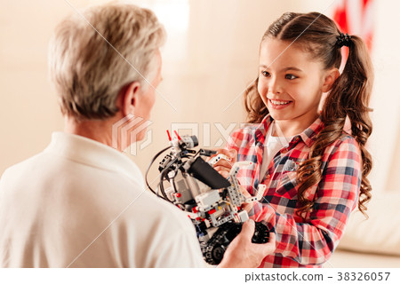 Smiling girl looking at grandfather holding robot Smiling girl looking at grandfather holding robot 38326057