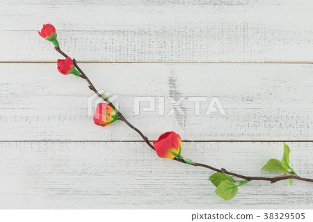 Fake red flowers with branch on white wood Fake red flowers with branch on white wood 38329505