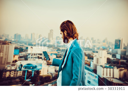 Western businessman using a phone on a rooftop with blurry city Western businessman using a phone on a rooftop with blurry city 38331911