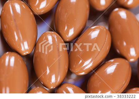 a scattering of brown capsules, tablets on a a scattering of brown capsules, tablets on a 38333222