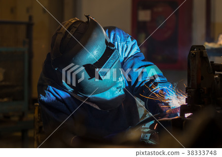Industrial worker with protective mask is welding  38333748