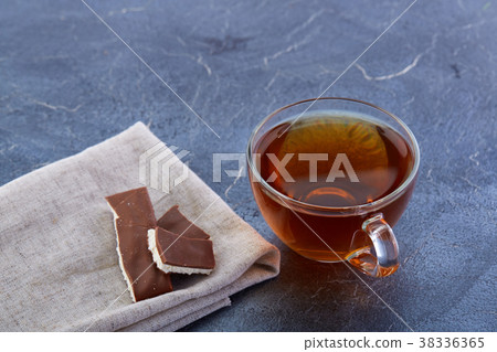 A glass cup of black tea with chocolate pieces on 38336365