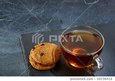 A glass cup of black tea with brownies on a dark 38336418
