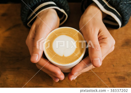 Girl holding a hot cup of coffee Girl holding a hot cup of coffee 38337202